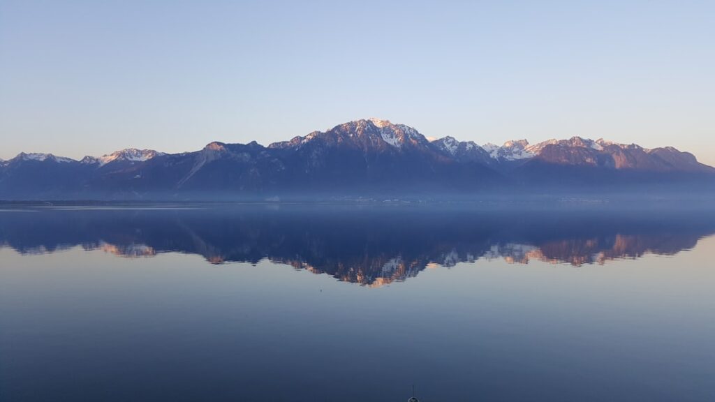 Scenic view of snow-capped mountains reflected in calm water, illustrating tranquility and nature, relevant to mental health themes in therapy and OCD management.