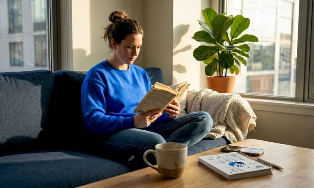 Woman reading quietly in sunlit living room