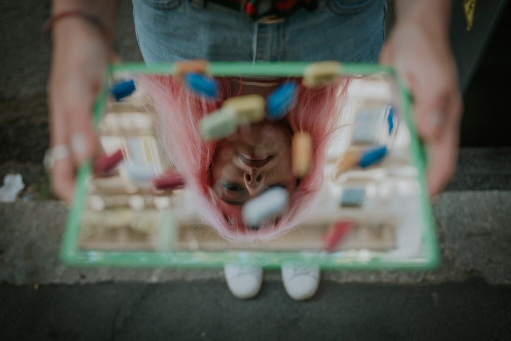 Person with pink hair playing miniature air hockey game, mental health and well-being.