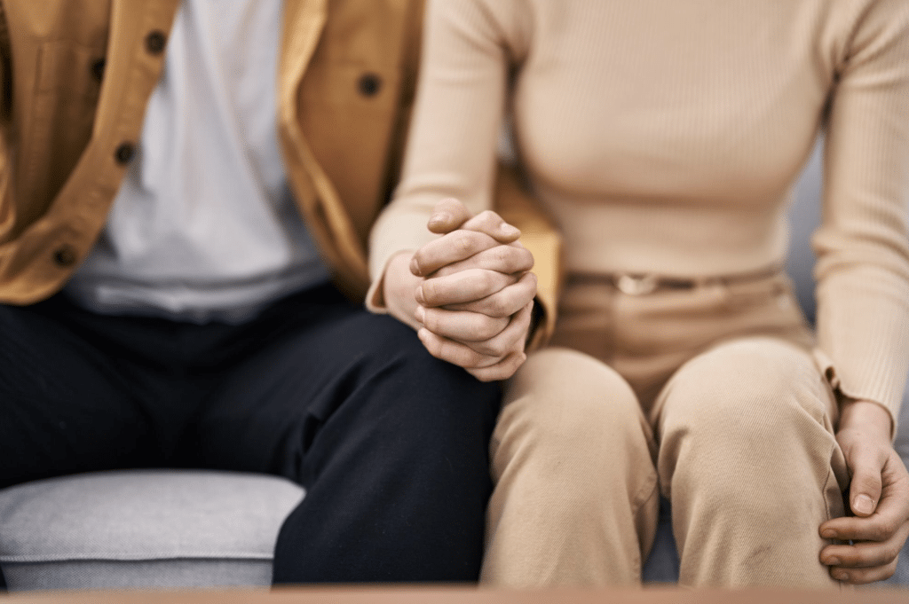 Couple holding hands on a couch during a couples therapy session in Paramus, New Jersey