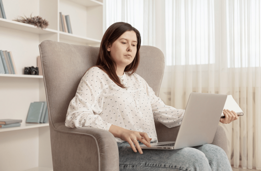 Woman in an armchair using a laptop for an online therapy session with a Paramus, New Jersey therapist