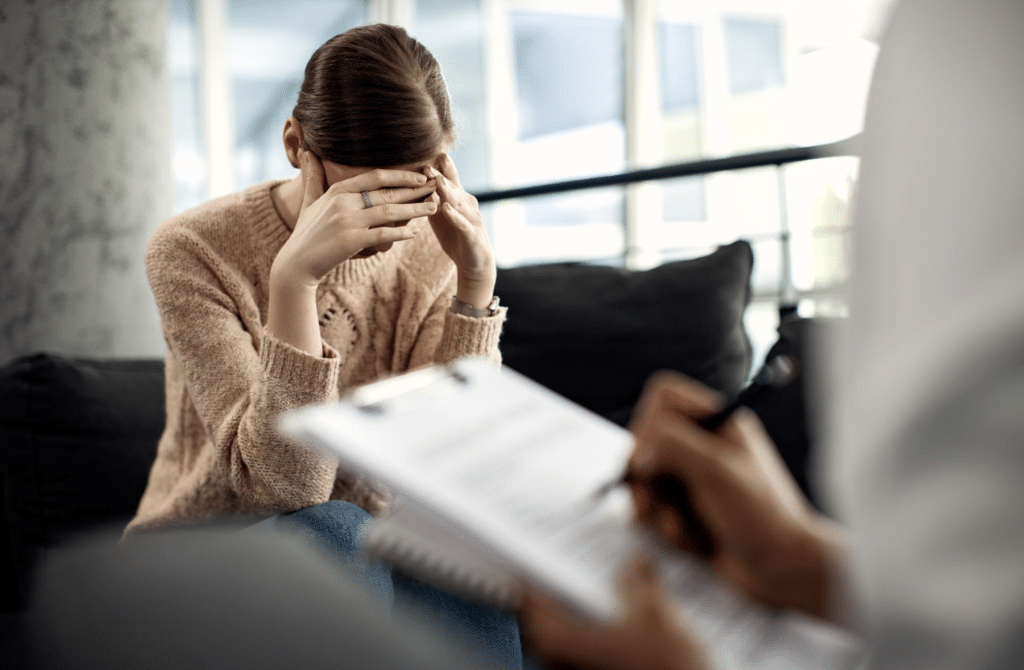Woman with her head in her hands while a therapist takes notes during a trauma therapy session in Paramus, New Jersey